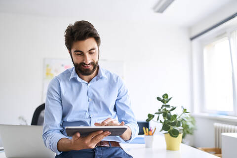 Geschäftsmann benutzt ein digitales Tablet in seinem Büro, lizenzfreies Stockfoto