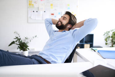 Smiling businessman sitting at a desk - BSZF01133