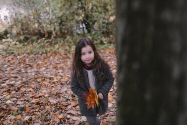 Porträt eines kleinen Mädchens, das im Herbst Blätter sammelt - OGF00040