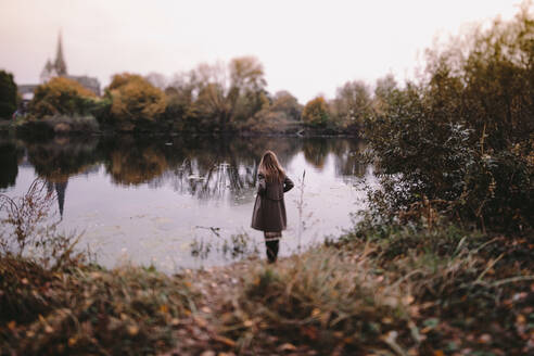 Back view of woman standing at water in autumn - OGF00048