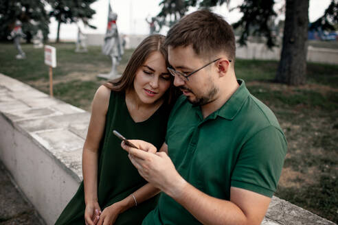 Ehepaar schaut im Freien auf sein Smartphone - OGF00066