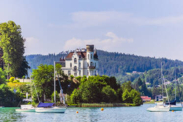 Sailboats moored at lake by church in Woerthersee against sky - THAF02531