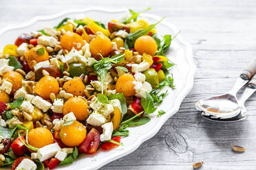 Nahaufnahme von Melonensalat in einem Teller mit Löffeln auf einem Holztisch - SARF04338