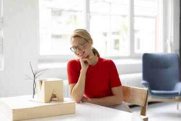 Young woman in office with architectural model on desk - JOSF03449