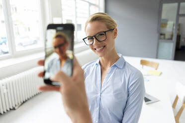 Smartphone picture of young businesswoman in office - JOSF03450