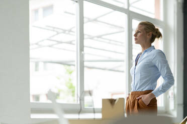 Serious young woman in office with architectural model on desk - JOSF03481