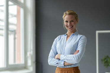 Portrait of smiling young businesswoman in office - JOSF03483