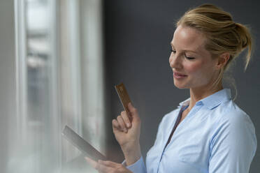 Smiling young woman with tablet and credit card - JOSF03485