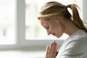 Smiling young woman with closed eyes and clasped hands - JOSF03509