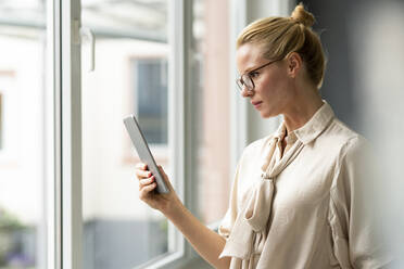 Young businesswoman using tablet at the window - JOSF03526