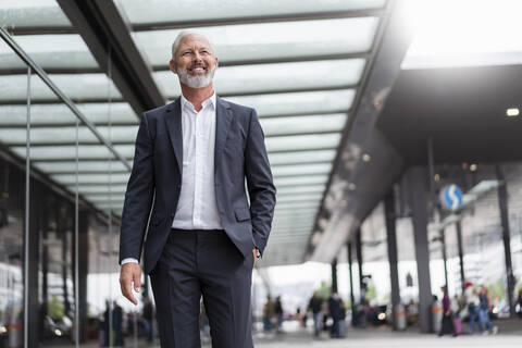 Lächelnder reifer Geschäftsmann in der Stadt unterwegs, lizenzfreies Stockfoto