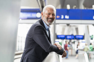 Portrait of smiling mature businessman at the station platform - DIGF07455