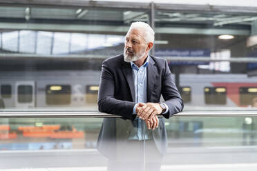 Mature businessman at the station platform looking around - DIGF07456