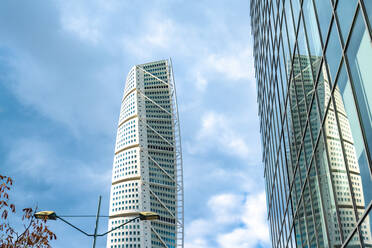Low angle view of turning torso tower reflecting on glass building against sky - TAMF01791