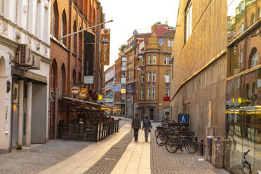 Rear view of people walking on street amidst residential buildings in Malmo city - TAMF01807