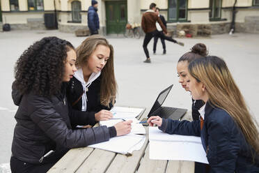 Multiethnische Freundinnen im Teenageralter lernen am Tisch auf dem Schulhof - MASF12830