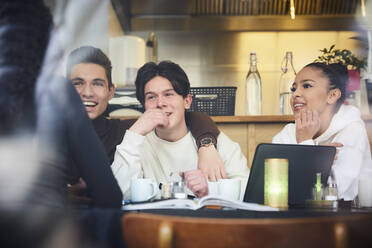 Lächelnde männliche und weibliche Teenager-Freunde sitzen am Tisch im Restaurant - MASF12845