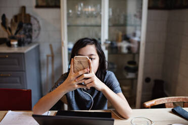 Boy using smart phone while doing homework at home - MASF12894