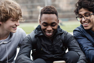 Cheerful male friends using social media after sports practice during winter - MASF12908