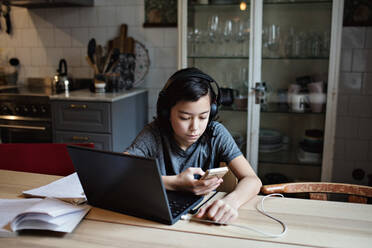 Boy using mobile phone for homework at home - MASF12922