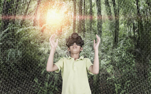 Gemischtrassiger Junge trägt Virtual-Reality-Brille in abgelegenem Wald - BLEF09705