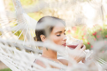 Caucasian woman drinking cocktail in hammock - BLEF09721