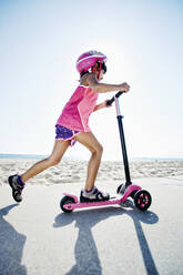 Gemischtrassiges Mädchen fährt Roller am Strand - BLEF09732