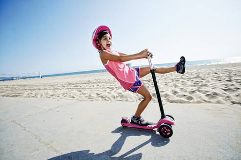 Girl riding scooter at beach - BLEF09734