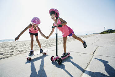 Mädchen fahren Skateboard und Roller am Strand - BLEF09735