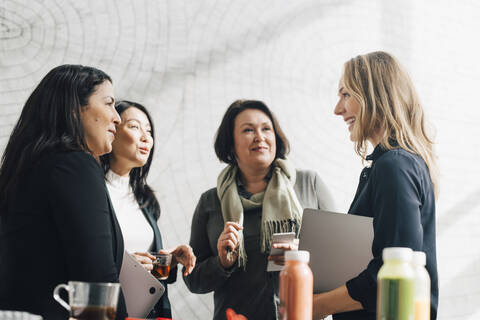 Weibliche Kollegen hören einer Geschäftsfrau in einer Besprechung auf einer Konferenz zu, lizenzfreies Stockfoto