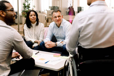 Business colleagues looking at disabled sales manager during meeting in office - MASF13027