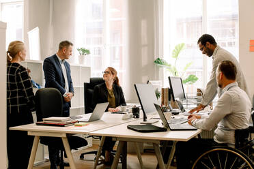 Business professionals working together at desk in office - MASF13056