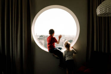Siblings by window in hotel room - MASF13073