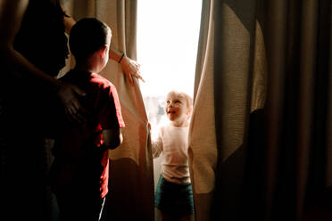 Mädchen steht am Fenster und sieht die Mutter mit dem Jungen im Hotelzimmer - MASF13077