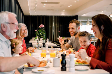 Fröhliche Familie im Gespräch beim Essen am Tisch im Restaurant - MASF13107