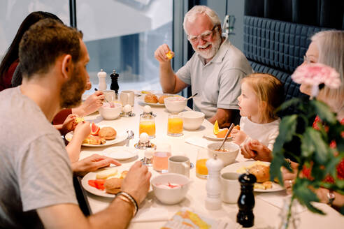 Blick von oben auf eine Mehrgenerationenfamilie, die in einem Restaurant am Tisch isst - MASF13108