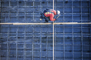 Kaukasischer Arbeiter nagelt Bretter auf einer Baustelle - BLEF09819