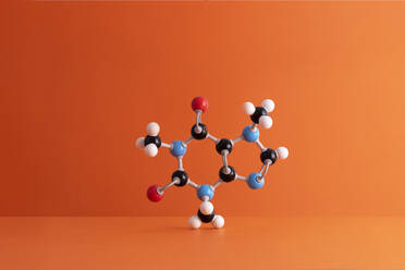 Caffeine formula's molecular structure over orange background - DRBF00156