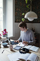 Teenage boy E-learning while using laptop on table at home - MASF13141