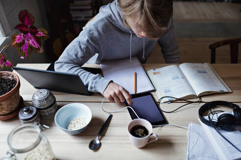 Hohe Winkel Ansicht der Teenager-Junge mit digitalen Tablet beim Lernen auf dem Tisch zu Hause - MASF13143