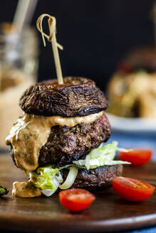 Nahaufnahme eines frischen Burgers mit Kirschtomaten auf einem Serviertablett - SBDF03989