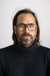 Porträt eines selbstbewussten reifen Mannes mit Brille vor weißem Hintergrund - DMOF00183