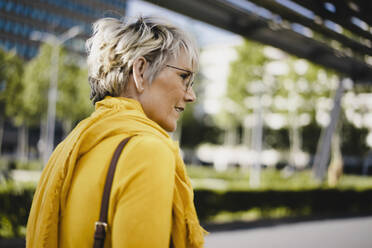 Reife Frau mit Brille und gelber Kleidung im Freien - KNSF06095