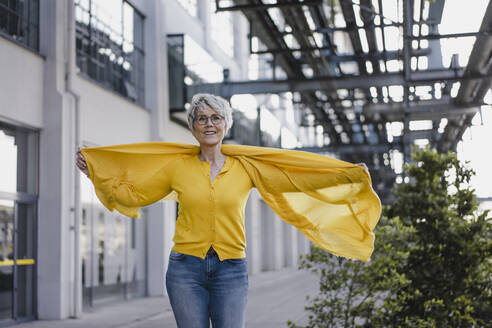 Porträt einer lächelnden reifen Frau mit gelber Strickjacke und Schal - KNSF06115