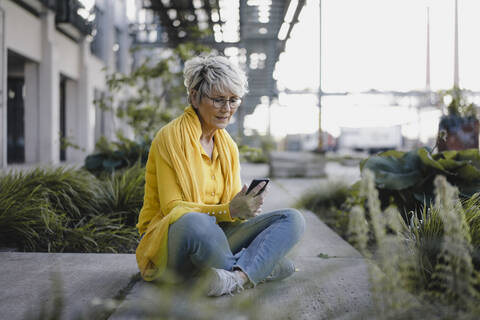 Mature woman using smartphone outdoors stock photo