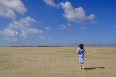Volle Länge Rückansicht von Teenager-Mädchen zu Fuß auf Sand am Strand während des sonnigen Tages - LBF02626