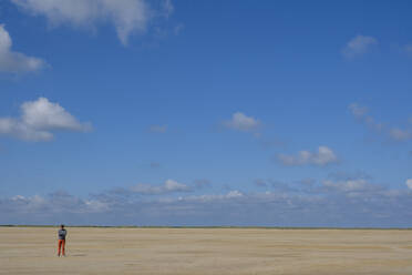 Reifer Mann in voller Länge am Strand stehend gegen blauen Himmel an einem sonnigen Tag - LBF02640