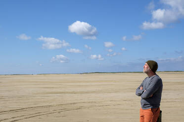 Nachdenklicher reifer Mann steht am Strand gegen blauen Himmel an einem sonnigen Tag - LBF02641