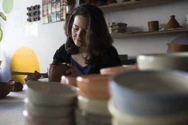 Potter shaping clay in her workshop - ABZF02418