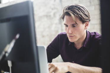 Männlicher Computerprogrammierer mit Laptop bei der Arbeit im Büro - MASF13319